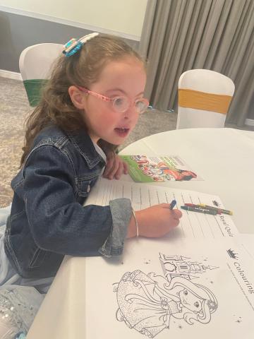 Phoebe colours activity sheets at a table